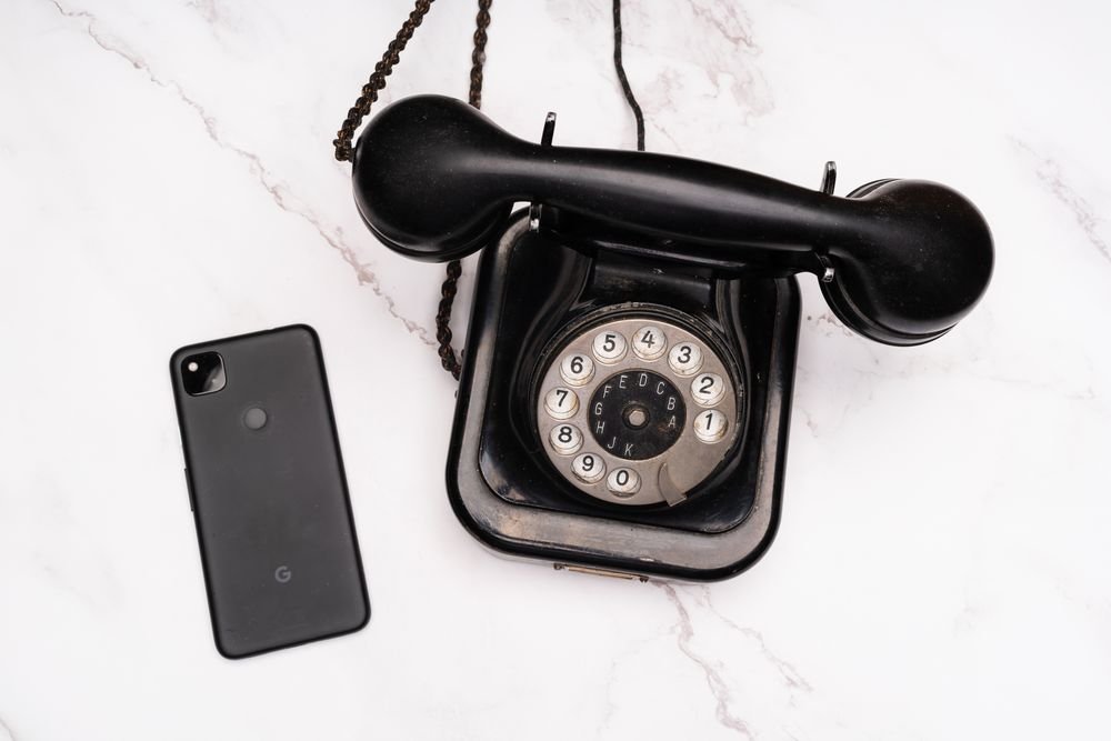 Evolution of mobile phones from rotary phone to modern smartphone on a marble surface