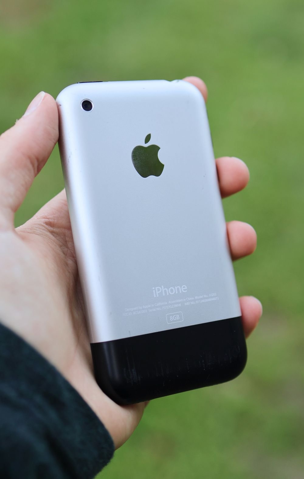 Person holding a classic vintage iPhone outdoors