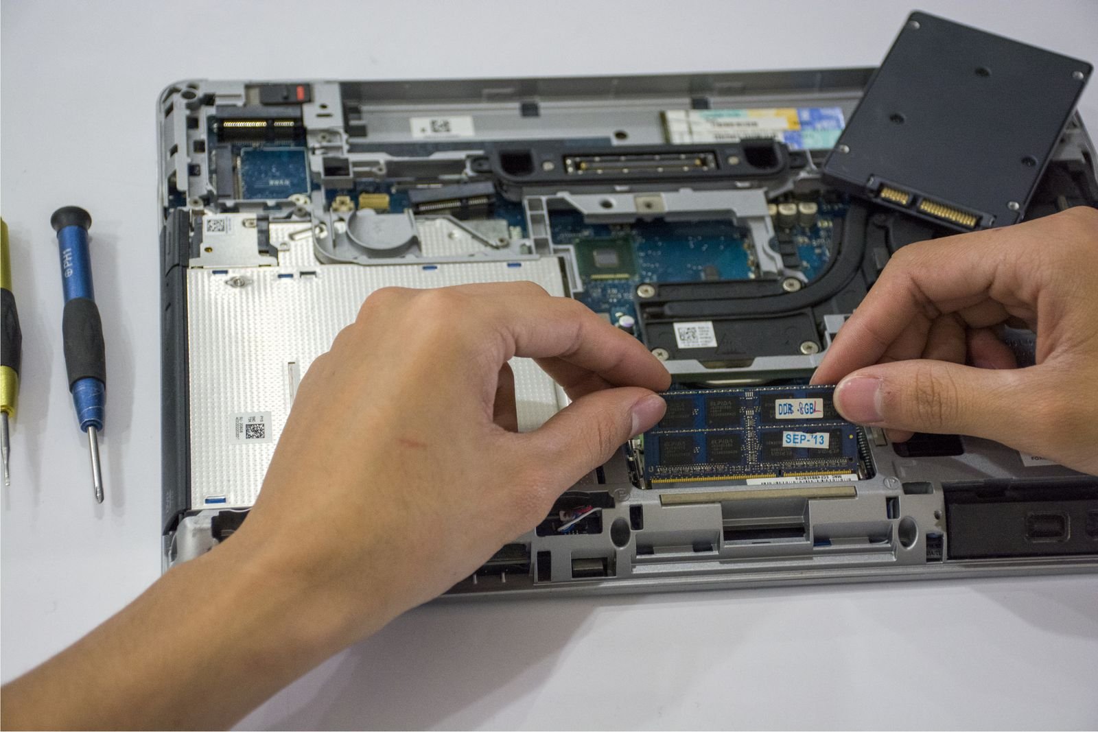 Technician upgrading the internal components of a laptop with tools